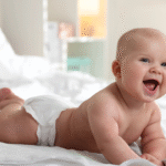 bebê alegre na cama usando uma das melhores fraldas do mercado